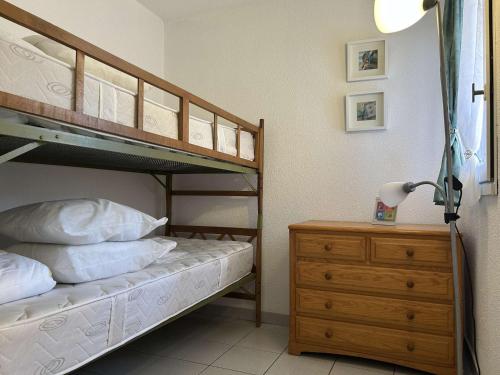 a bedroom with bunk beds and a dresser with a lamp at Appartement cosy, 2 pièces, proche plage et parking sécurisé - FR-1-229D-150 in Fleury