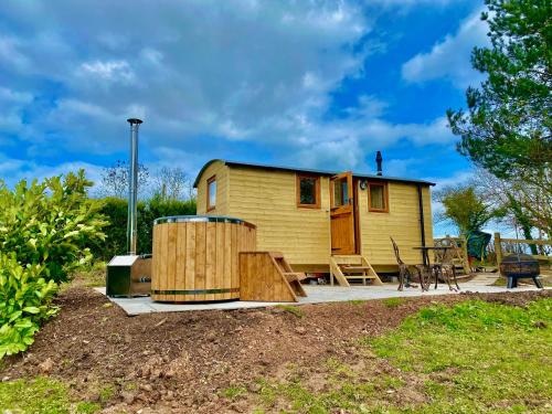 a small yellow tiny house with a patio and a table at Off-Grid Glamping - Quiet, Starry Escape in Yarpole