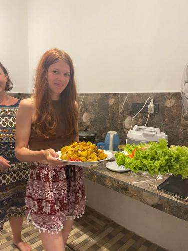 a woman holding a plate of food in a kitchen at Royal Palace Mirissa in Mirissa