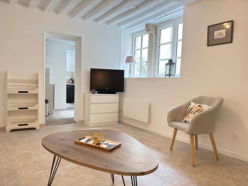 un salon avec une table, une chaise et une télévision dans l'établissement Le Clos Guillaume, à Bayeux