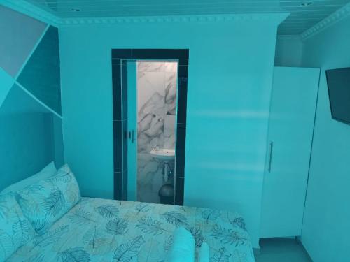 a blue room with a bed and a bathroom at Boblodge in Cape Town