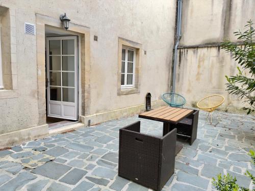 une table et une télévision assises sur un patio en pierre dans l'établissement Le Clos Guillaume, à Bayeux