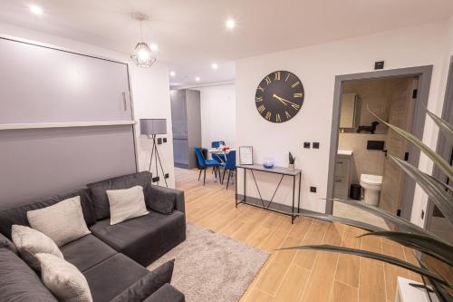 a living room with a couch and a clock on the wall at Chic 2King BD Apt London with Ensuite & Pull Out Bed in Finchley