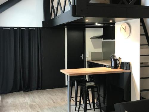 une cuisine avec des murs noirs et une table avec des tabourets dans l'établissement Hypercentre Calme Proche Massey, à Tarbes