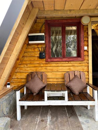Dos sillas en la parte delantera de una cabaña con ventana. en Eco kutak 3, en Mojkovac