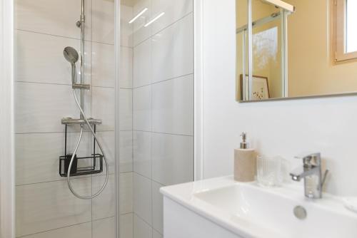 une salle de bain blanche avec une douche et un lavabo dans l'établissement La passerelle - vue et proximité cathédrale, terrasse, parking privé, à Albi