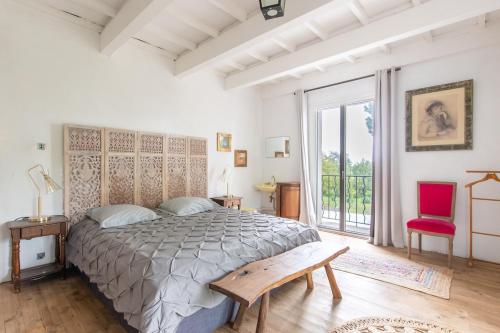 une chambre avec un grand lit et une chaise rouge dans l'établissement Parenthèse enchantée, mas de caractère, grande piscine, parc paysagé aux portes de Montpellier et des plages, à Mauguio