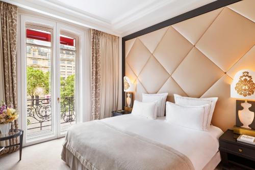 a bedroom with a large bed and a large window at Hôtel Barrière Fouquet's Paris in Paris