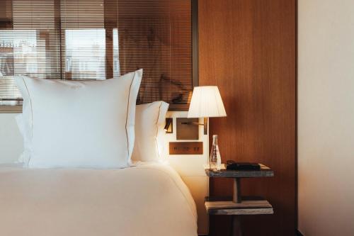 a bedroom with a bed and a table with a lamp at Hotel SAX Paris, LXR Hotels & Resorts in Paris