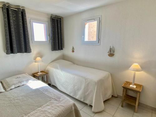 - une chambre avec 2 lits et 2 lampes sur les tables dans l'établissement Mazet vue mer - parking - wifi - clim - piscine, à Sainte-Maxime