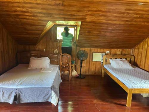 a woman standing in a room with two beds at SiQUIJOR SEA SHORE HOUSE in Siquijor