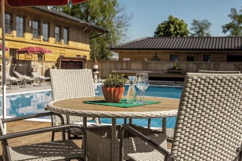 a table with a glass of wine and two chairs at Ferienwohnung MOOS 2 mit Wellnessnutzung in Ainring