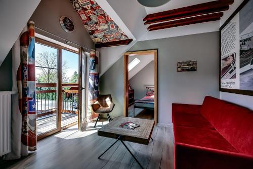 a living room with a red couch and a balcony at Jantarvia Car Museum , Pasja i Wypoczynek Noclegi z Klimatem in Jantar