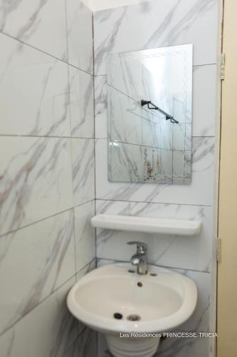 a white bathroom with a sink and a mirror at RESIDENCE PRINCESSE tricia in Cotonou