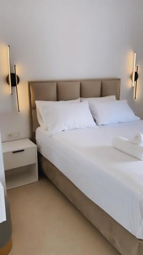 a bed with white sheets and pillows in a room at Milto's Apartment in Limenaria