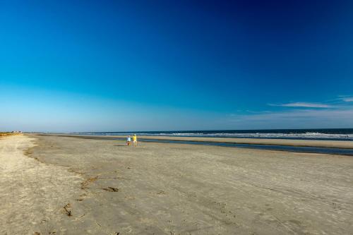 a person standing on a beach near the ocean at 46 Surfsong Road by Akers Ellis Rentals in Kiawah Island