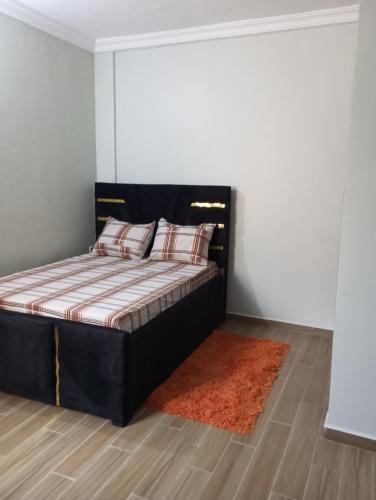 a bedroom with a black bed with an orange rug at Golfe de Makepe in Douala