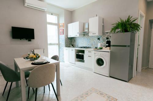 a kitchen with a table and a white refrigerator at Le Case delle Rose in Civitavecchia