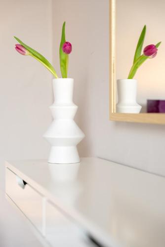two white vases with flowers on top of a dresser at Todd Crag - Amazing Views in Ambleside