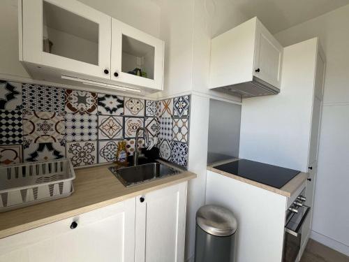 une petite cuisine avec des armoires blanches et un évier dans l'établissement Appartement en bord de mer avec Wi-Fi - Lavandou - FR-1-308-82, au Lavandou