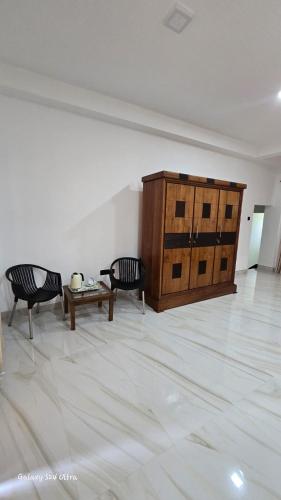 a living room with two chairs and a wooden cabinet at Kingston Estate in Digana