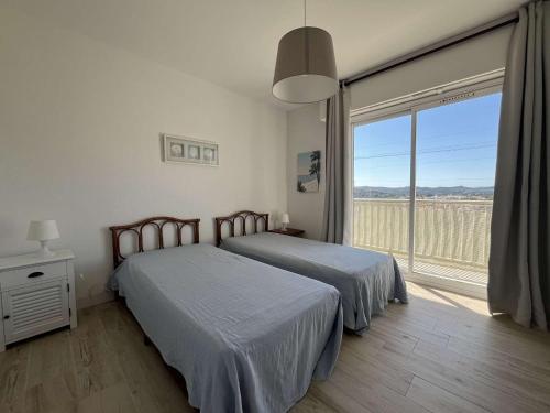 - 2 lits dans une chambre avec une grande fenêtre dans l'établissement Appartement en bord de mer avec Wi-Fi - Lavandou - FR-1-308-82, au Lavandou