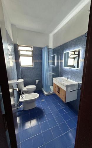 a blue tiled bathroom with a toilet and a sink at Ela's apartment 1 in Durrës