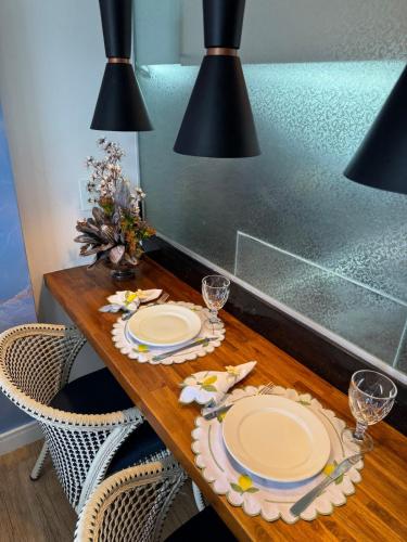 a dining room table with two plates and wine glasses at Ondina Apart Hotel 02 quartos Vista Mar in Salvador