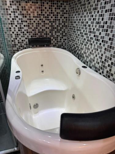 a white bath tub in a bathroom with black tiles at Ondina Apart Hotel 02 quartos Vista Mar in Salvador