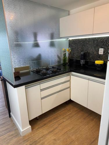 a kitchen with white cabinets and black counter tops at Ondina Apart Hotel 02 quartos Vista Mar in Salvador