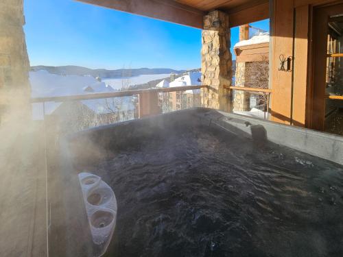 bañera de hidromasaje en un porche con vistas a las montañas en Tremblant Prestige - Équinoxe 164-2, en Mont-Tremblant