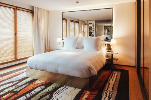 a bedroom with a large white bed and a mirror at Hotel SAX Paris, LXR Hotels & Resorts in Paris