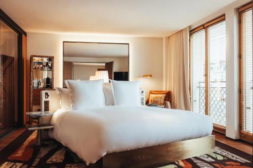 a bedroom with a large white bed and a mirror at Hotel SAX Paris, LXR Hotels & Resorts in Paris