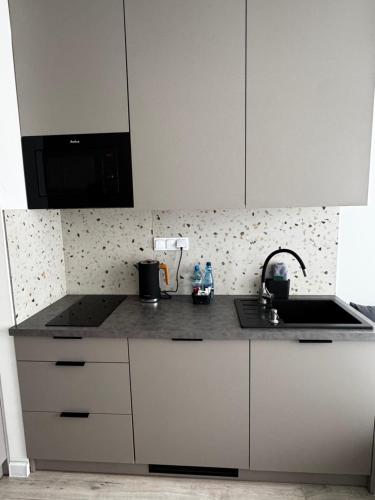 a kitchen with white cabinets and a sink at Platon Residence Apartments in Łódź