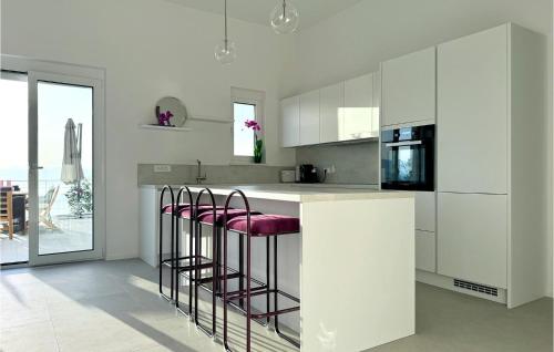 a kitchen with white cabinets and a counter with stools at Gorgeous Home In Dobrec With Sauna in Dobreć