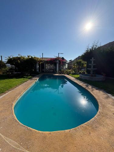 a blue swimming pool in front of a house at Cabañas Punta de Piedra in Punta de Piedra