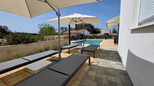 a patio with benches and an umbrella next to a pool at Residence Giardino in Ugljan