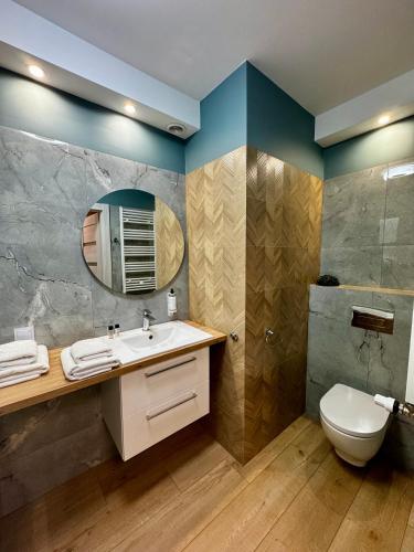 a bathroom with a sink and a toilet and a mirror at Platon Residence Apartments in Łódź