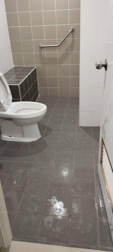 a bathroom with a toilet and a tiled floor at Nanzarie House in Bang Kew Yai