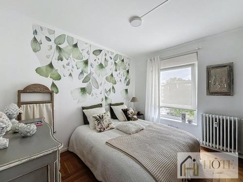 - une chambre avec un lit orné d'une fresque murale représentant des feuilles dans l'établissement L'Atelier Lumière-Centre Ville, à Dunkerque