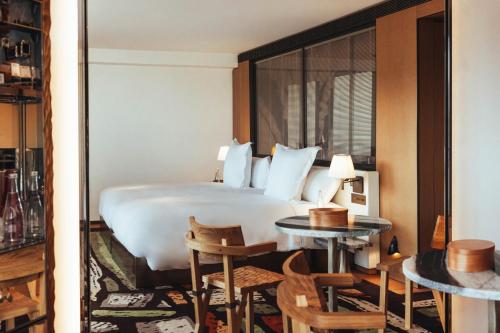 a hotel room with a bed and tables and chairs at Hotel SAX Paris, LXR Hotels & Resorts in Paris