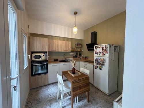 une cuisine avec une table et un réfrigérateur blanc dans l'établissement Maison cosy pour 2 à 4 personnes, proche de tout, à Boulogne-sur-Mer