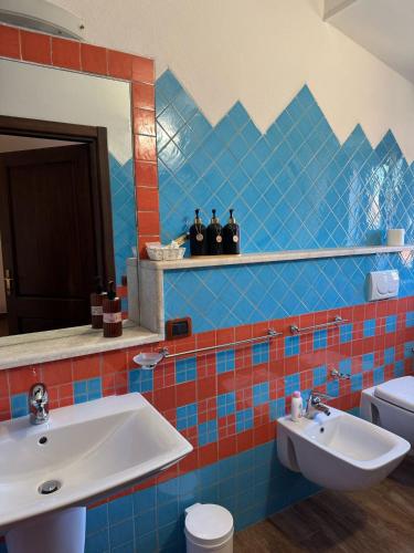 a blue tiled bathroom with a sink and a mirror at Il Gallo di Gallura in Tempio Pausania