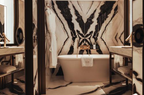 a bathroom with a tiger themed wallpaper and a bath tub at Hotel SAX Paris, LXR Hotels & Resorts in Paris