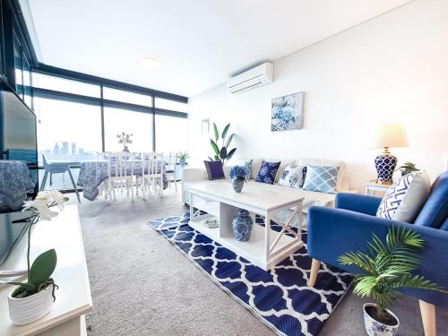a living room with a blue couch and a table at Hamptons Style 2BR & kid room w view in Olympic Park in Sydney