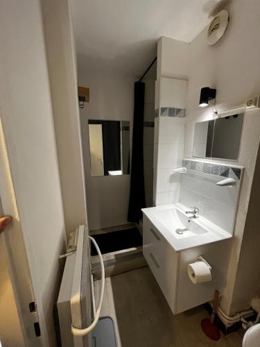 une salle de bain blanche avec un lavabo et un miroir dans l'établissement Studio le sergent, au Cap d'Agde