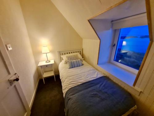 a small bedroom with a bed and a window at 2 Carrigreich in Scalpay