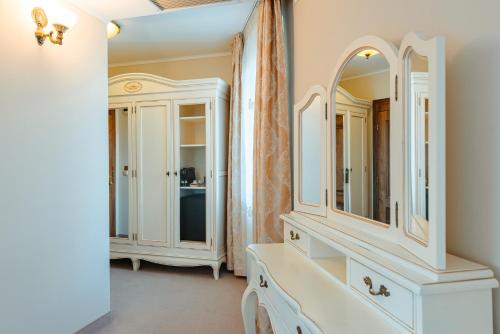 a bathroom with white cabinets and mirrors at SunGarden Golf & Spa Resort in Cluj-Napoca
