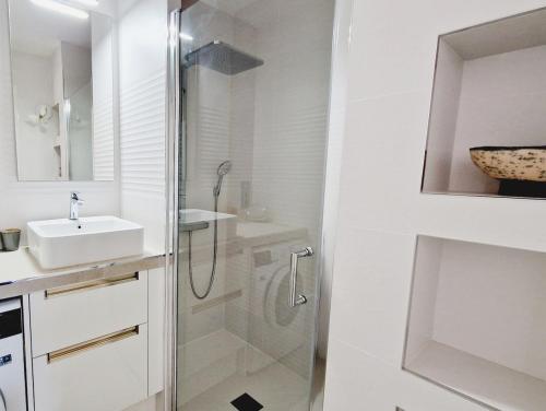 une salle de bain blanche avec une douche et un lavabo dans l'établissement L'Orée - Bel appartement balcon vue mer et parking, à Les Sables-dʼOlonne