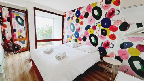 - une chambre avec un lit blanc et un mur coloré dans l'établissement L'Orée - Bel appartement balcon vue mer et parking, à Les Sables-dʼOlonne